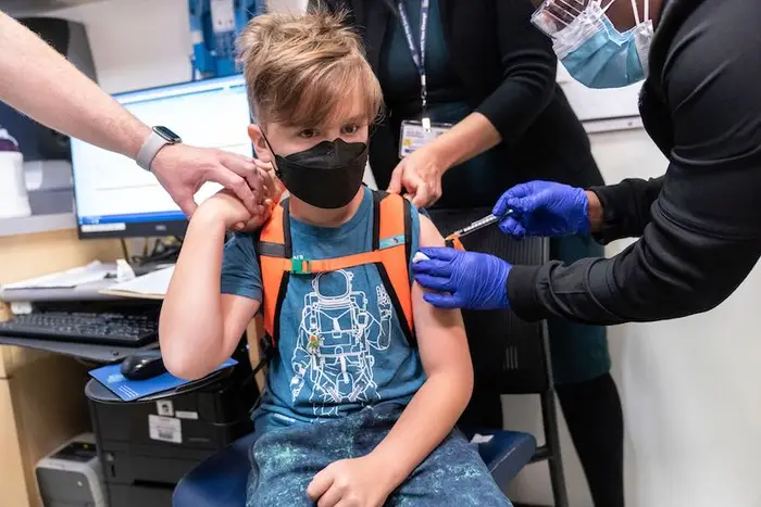 Registered Nurse Natasha McDannis inoculates Otto Linn-Walton, 8, wearing a black mask and blue astronaut t-shirt, with the first dose of the Pfizer-BioNTech COVID-19 vaccine for children at NYC Health + Hospitals Harlem Hospital, in New York